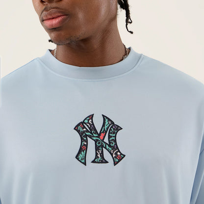 New Era New York Yankees MLB Mesh Infill Pastel Blue Oversized T-Shirt, front view displaying an embroidered Yankees logo with intricate floral patterns centred on the chest, set against a pastel blue fabric.