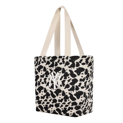 New Era New York Yankees MLB Cow Jacquard Cream Tote Bag, three-quarter view showing the cow print pattern in black and cream, with white embroidered New York Yankees logo centrally placed, and two cream handles.