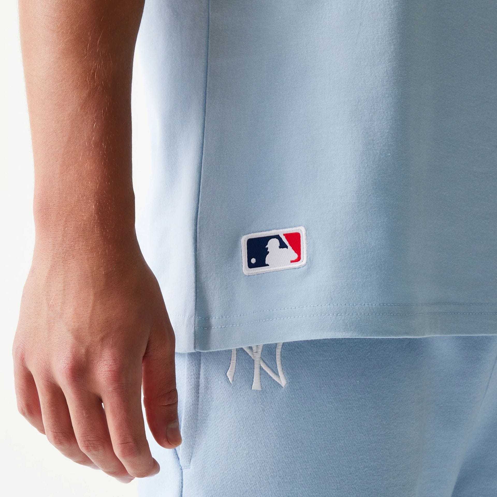 The model is wearing this MLB League Essential New York Yankees Sleeveless T-Shirt in pastel blue. 4