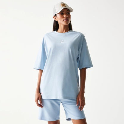 New Era New York Yankees MLB Midi Pastel Blue Oversized T-Shirt, front view on-model showing the embroidered white New York Yankees logo in the centre of the chest, styled with matching pastel blue shorts.