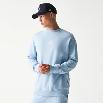New Era New York Yankees MLB Midi Blue Oversized Crew Neck Sweater, on-model view showing the relaxed fit and white embroidered NY logo on the chest, with ribbed cuffs and hem complementing the soft blue fabric.