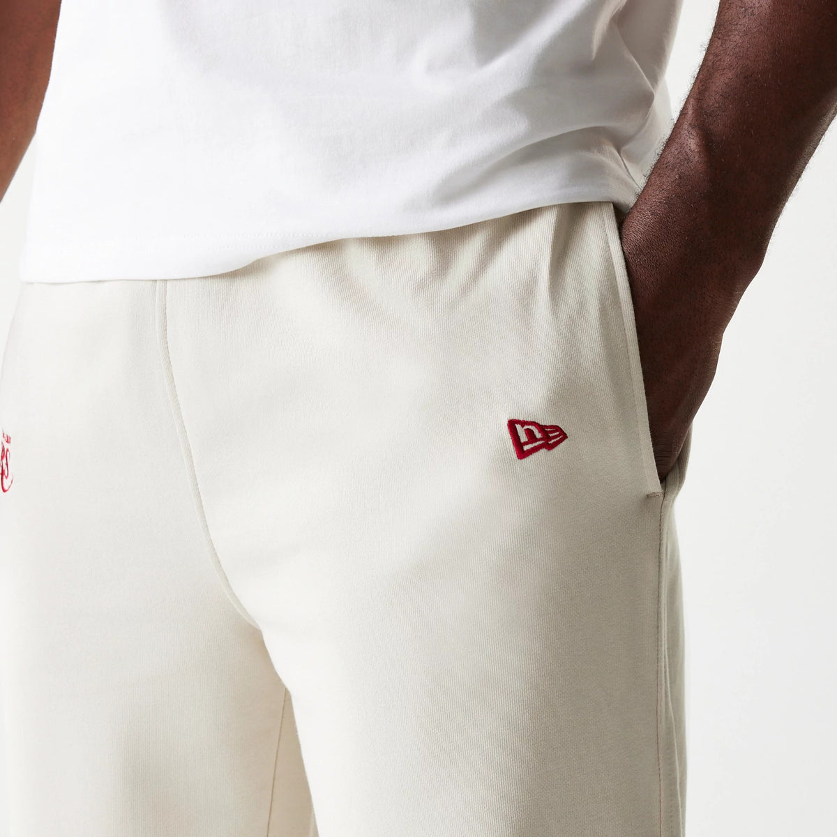 New Era LA Lakers NBA League Essential Cream Joggers, three-quarter view showing the red embroidered New Era flag logo near the right pocket, with a cream fabric and an elastic waistband.