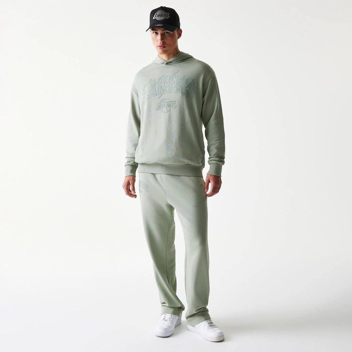 New Era LA Lakers NBA Pastel Green Straight Leg Joggers, front view on a model wearing a matching hoodie and black cap, showing the relaxed fit, elasticated waistband and LA Lakers logo embroidered on the left thigh.