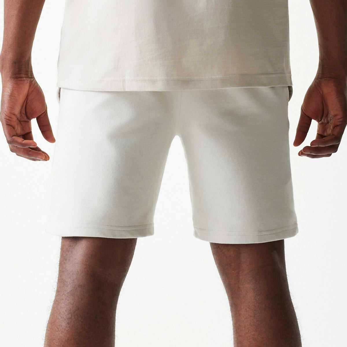 New Era LA Lakers NBA League Essential Cream Shorts, back view displaying the plain cream design with a simple cut above the knee, no logos or graphics, styled with a light-coloured top.