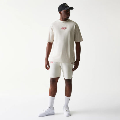 New Era LA Lakers NBA League Essential Cream Shorts, on-model view showing cream shorts with an embroidered Lakers logo on the left leg, paired with a matching cream T-shirt featuring the same logo centrally on the chest.