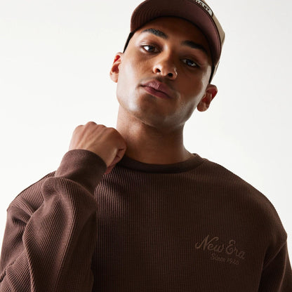 The model is wearing this New Era Script Waffle Crew Neck Sweater in brown. 8