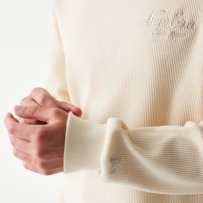 The model is wearing this New Era Script Waffle Crew Neck Sweater in light beige. 6
