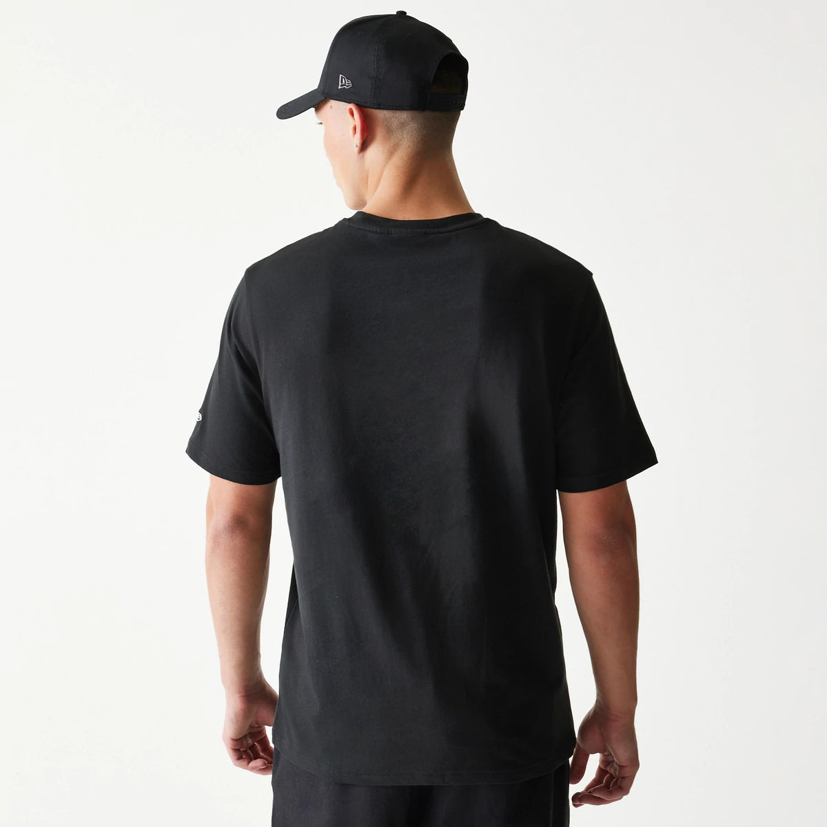 New Era Chicago Bulls NBA Ball Graphic Black T-Shirt, back view on a model styled with a black cap, displaying a plain black back with short sleeves and a embroidered New Era logo on the left sleeve.