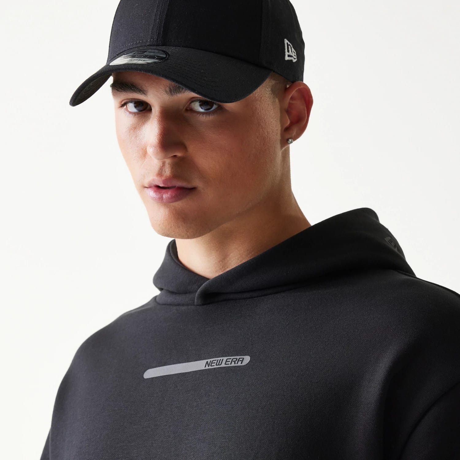 The model is wearing this New Era Tech Strip Oversized Pullover Hoodie in black. 8