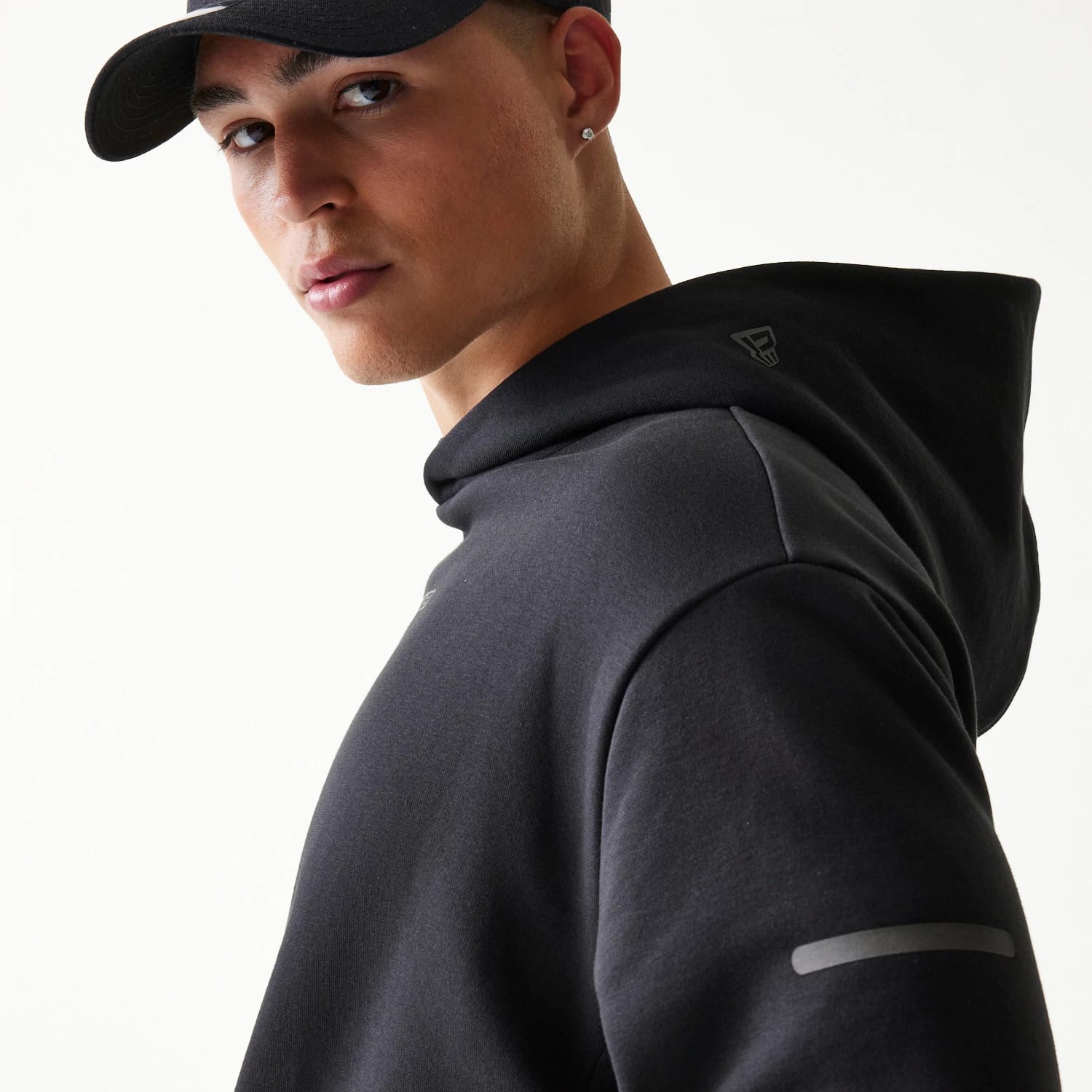 The model is wearing this New Era Tech Strip Oversized Pullover Hoodie in black. 5