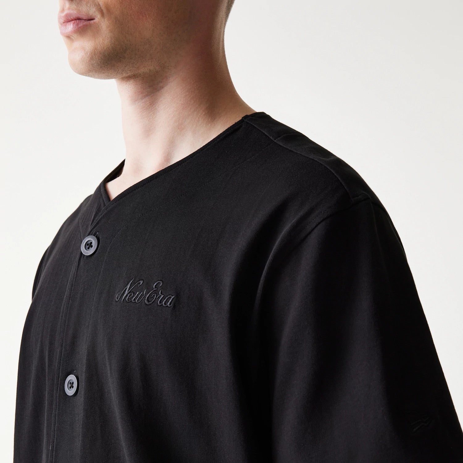 The model is wearing this New Era Open Heritage Script T-Shirt in black. 4