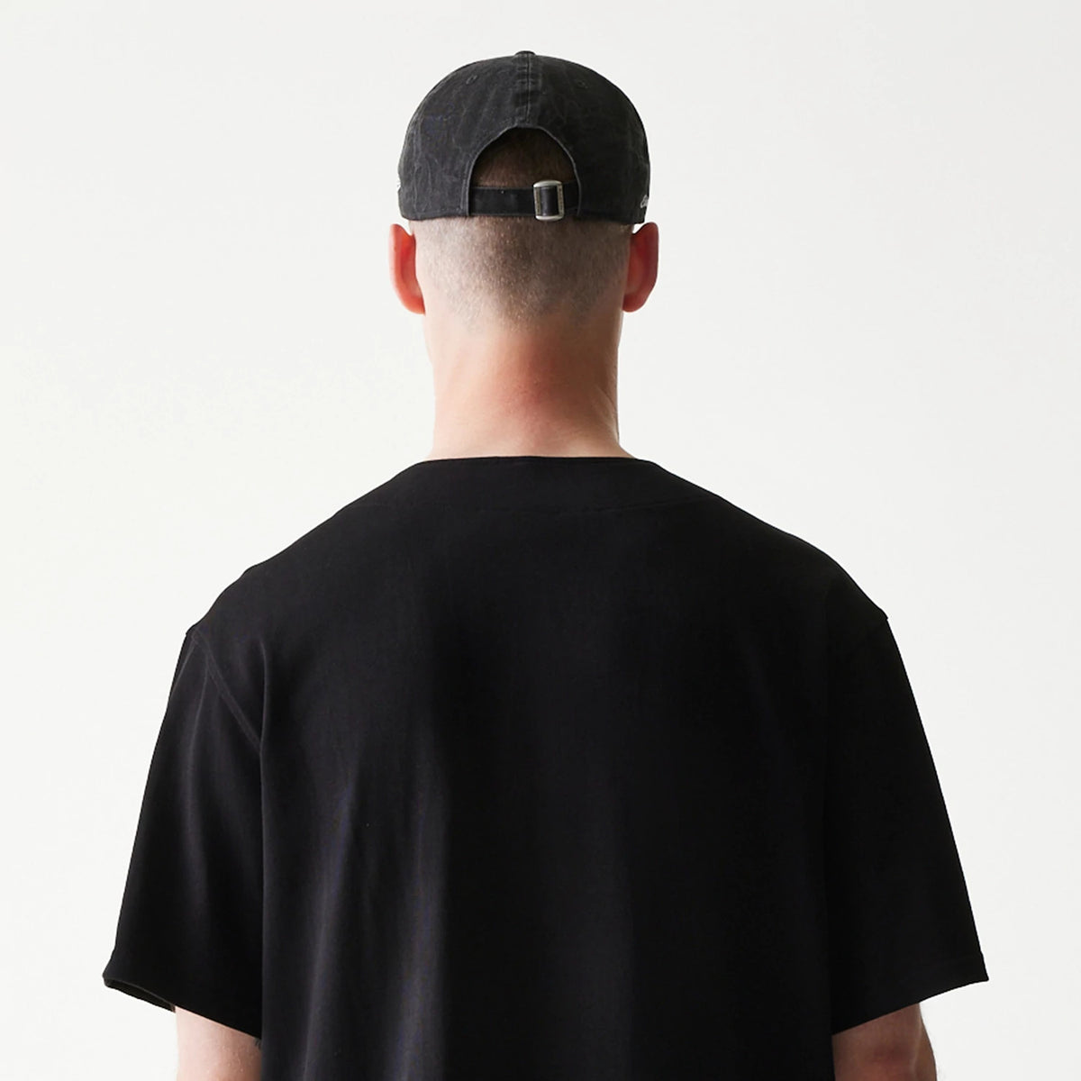 The model is wearing this New Era Open Heritage Script T-Shirt in black. 7