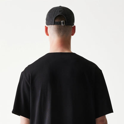 The model is wearing this New Era Open Heritage Script T-Shirt in black. 7