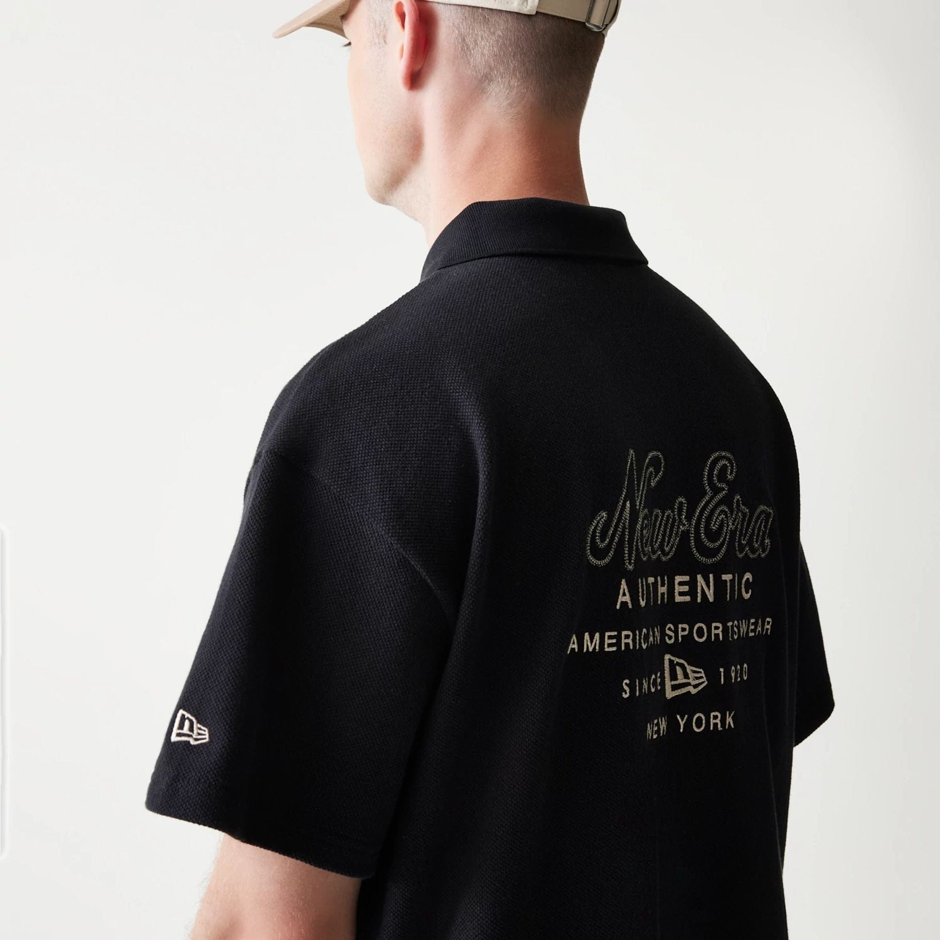 The model is wearing this New Era Graphic Polo T-Shirt in black. 5