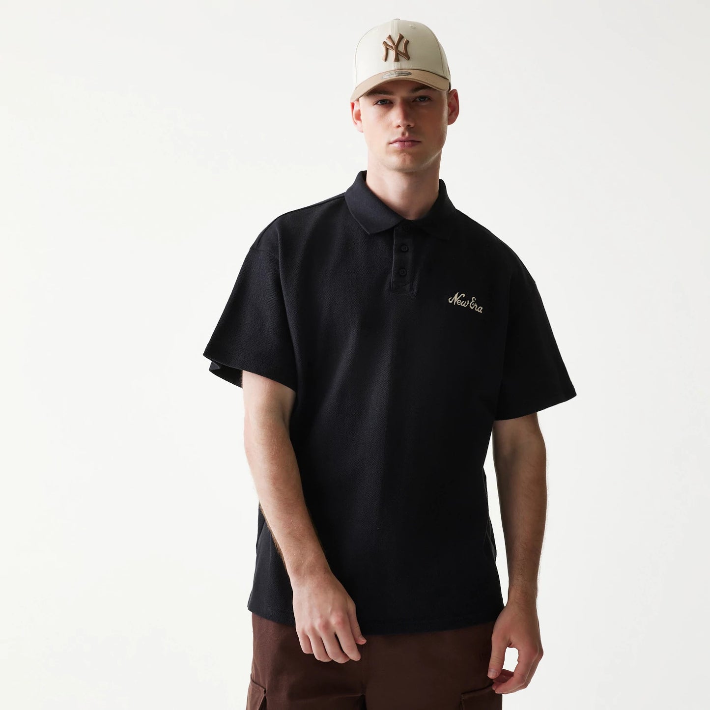 The model is wearing this New Era Graphic Polo T-Shirt in black. 1