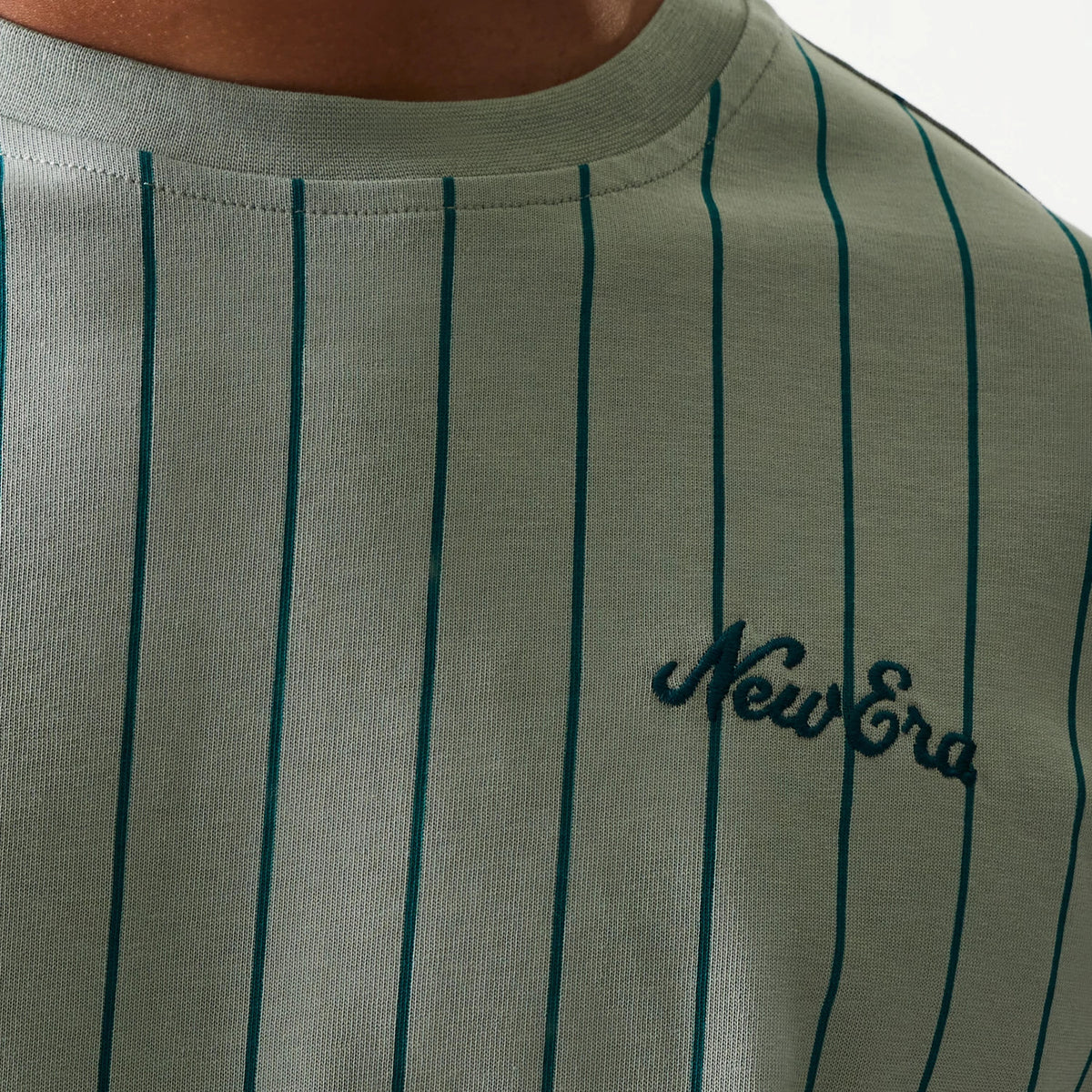 New Era Pinstripe Pastel Green Oversized T-Shirt, front view showing narrow dark green pinstripes running vertically down the shirt and an embroidered New Era logo in dark green positioned on the left side of the chest.