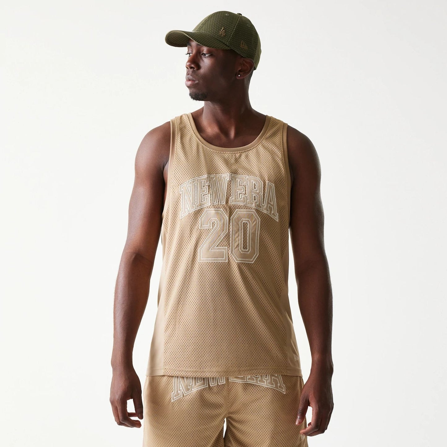 The model is wearing this New Era Mesh Tank Top in light beige. 3