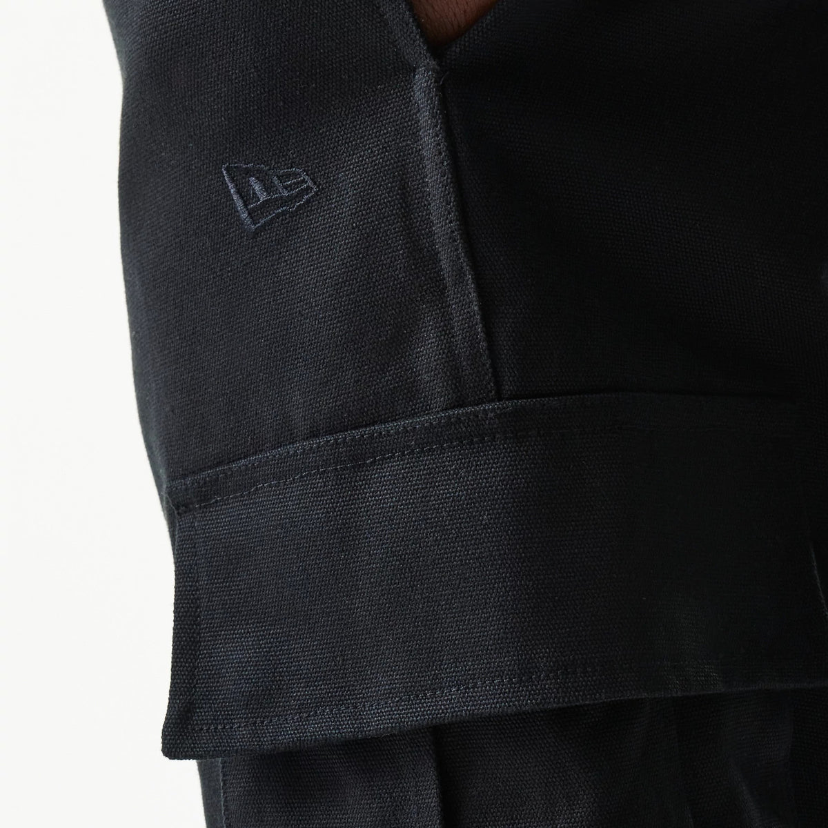 New Era Black Straight Leg Cargo Joggers, close-up view showing the textured fabric and the embroidered New Era flag logo above the flap of the side cargo pocket.