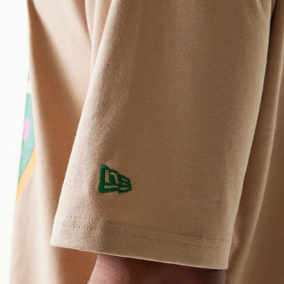 The model is wearing this New Era Orange Fruit Graphic Oversized T-Shirt in light beige. 5