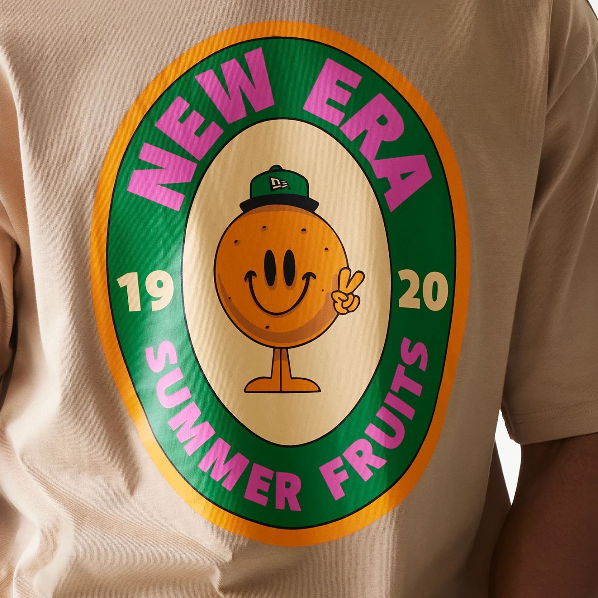 The model is wearing this New Era Orange Fruit Graphic Oversized T-Shirt in light beige. 6