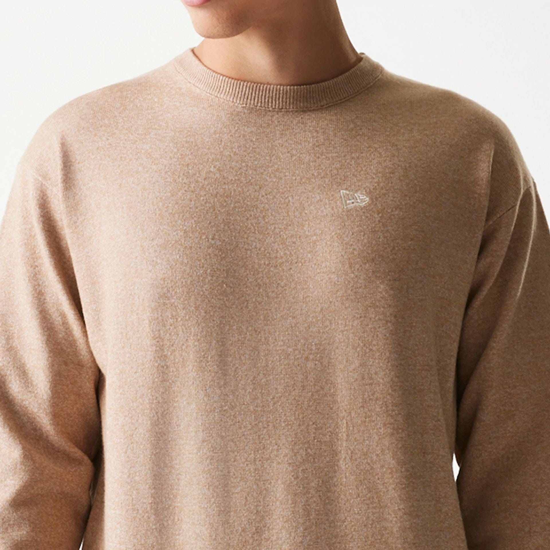 The model is wearing this New Era Essential Flag Knitted Sweater in light beige. 4