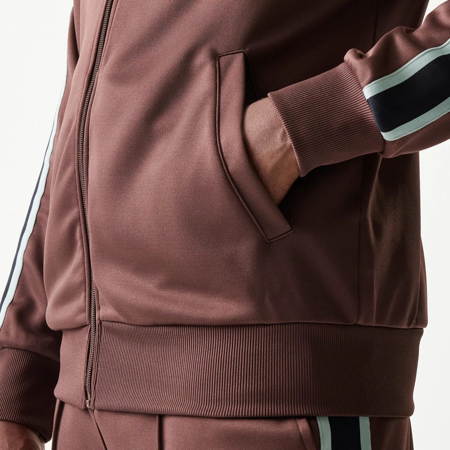 The model is wearing this New Era Script Track Jacket in brown. 7