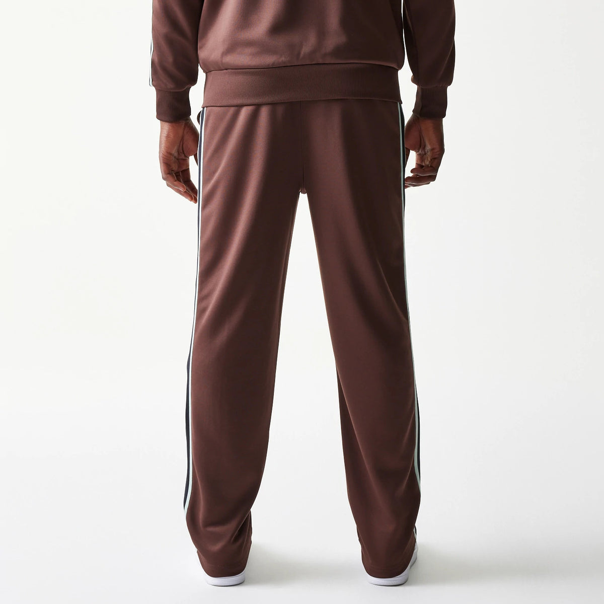 New Era Script Brown Straight Leg Joggers, rear view on a model showing the relaxed fit with white side stripes, elasticated waistband, and straight leg design highlighting the brown fabric.