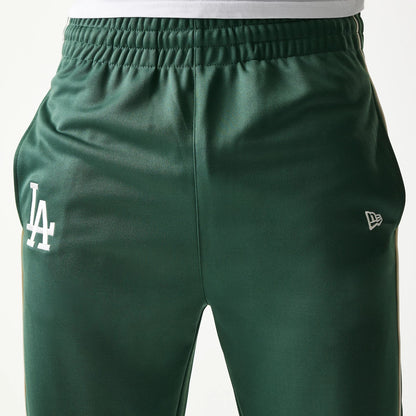 New Era LA Dodgers MLB Piping Dark Green Straight Leg Joggers, front view showing the white LA logo on the left thigh and the New Era flag logo on the right, with an elasticated waistband above a straight leg fit.