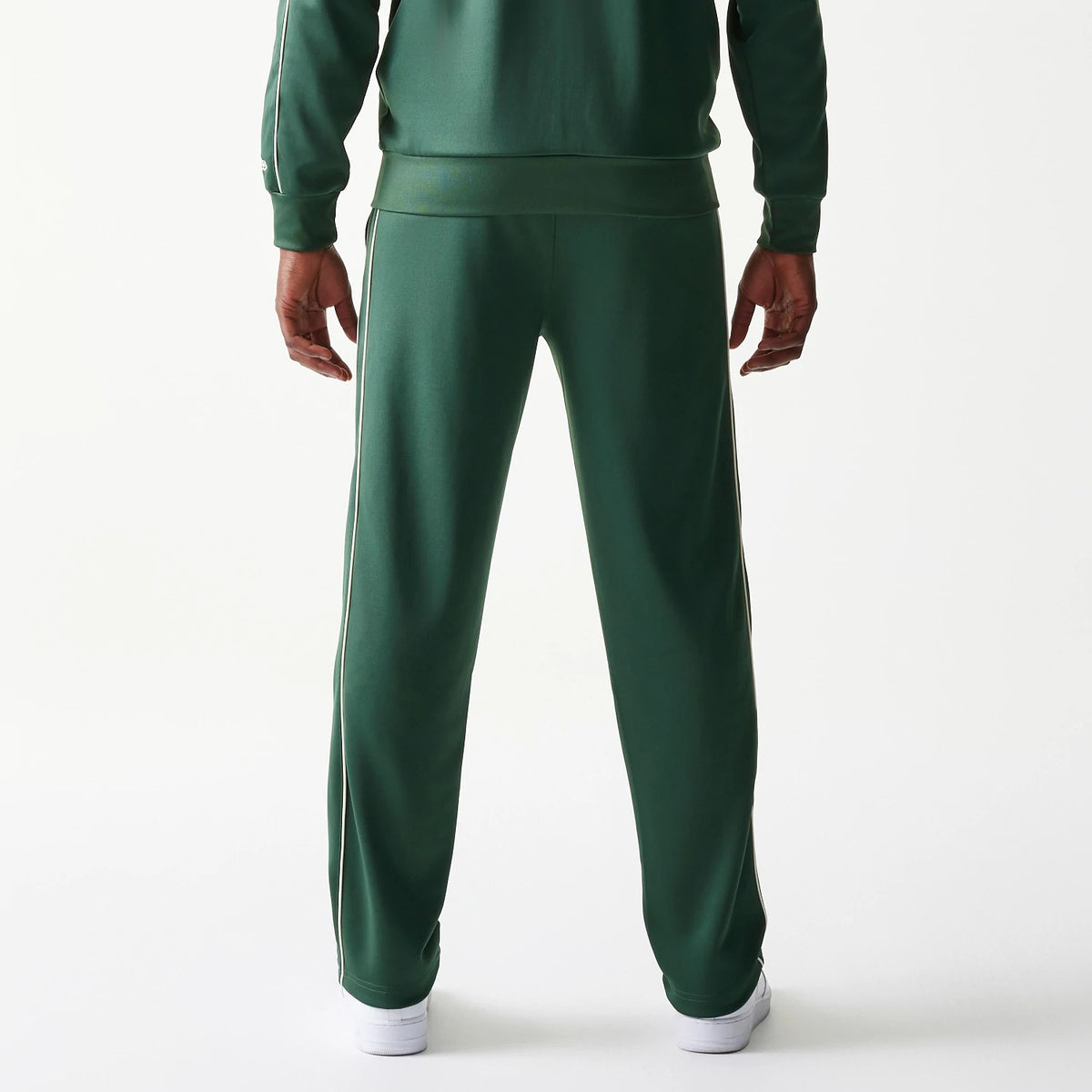 New Era LA Dodgers MLB Piping Dark Green Straight Leg Joggers, rear view on a model with white trainers, showing the piping along the sides and an elasticated waistband, presenting a relaxed fit in dark green fabric.