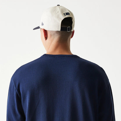 New Era New York Yankees MLB Essential Navy Knitted Sweater, rear view on a model also wearing a light-coloured adjustable cap, showing the plain back of the sweater with a ribbed neckline and the MLB logo on the cap's back strap.