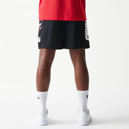 New Era Chicago Bulls NBA Mesh Black Shorts, back view on a model featuring white Chicago lettering running vertically down the right leg and the Bulls logo in colour on the left, styled with a red top and white trainers.