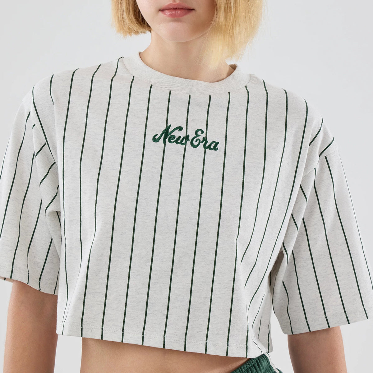 Womens New Era Pinstripe Pastel Grey Cropped T-shirt, front view showing green embroidered New Era logo centred on the chest, narrow vertical green pinstripes evenly spaced across the light grey cropped fabric.