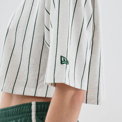 Womens New Era Pinstripe Pastel Grey Cropped T-shirt, side view showing vertical dark green pinstripes along the light grey fabric and an embroidered green New Era logo on the lower sleeve, styled with dark green shorts.