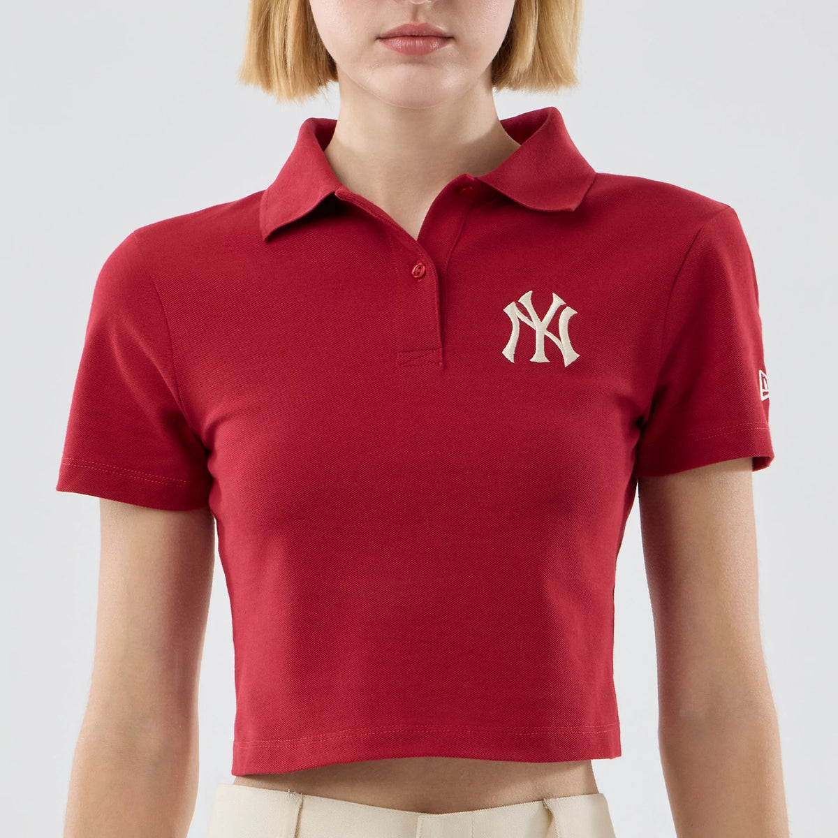 New Era New York Yankees Womens MLB Dark Red Cropped Slim Polo T-shirt, front view showing a raised white NY Yankees logo on the chest and a New Era embroidered logo on the left sleeve, styled on a model wearing light trousers.