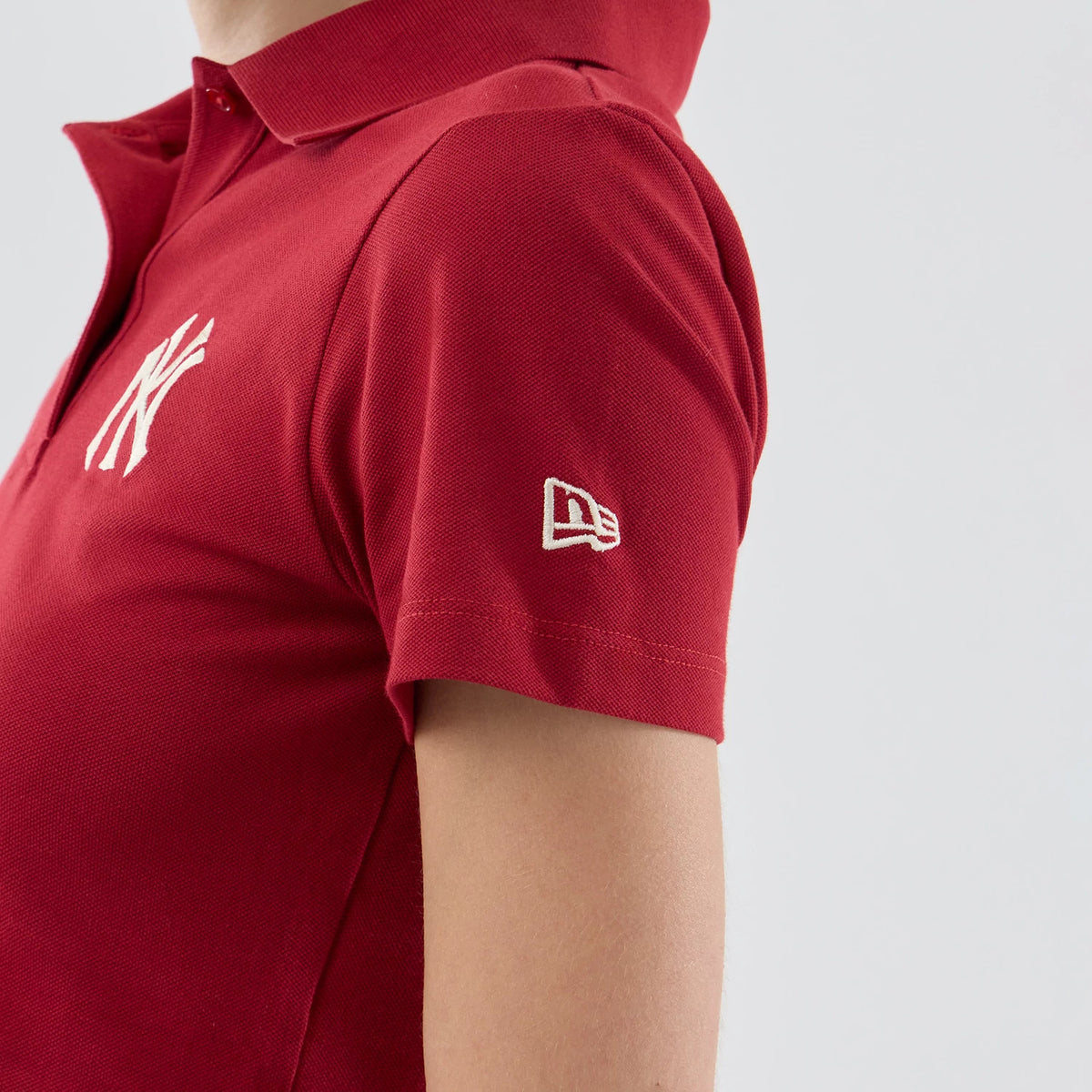 New Era New York Yankees Womens MLB Dark Red Cropped Slim Polo T-shirt, side view showing the NY logo embroidered on the chest and a white embroidered New Era logo on the short sleeve, with a classic ribbed collar at the top.