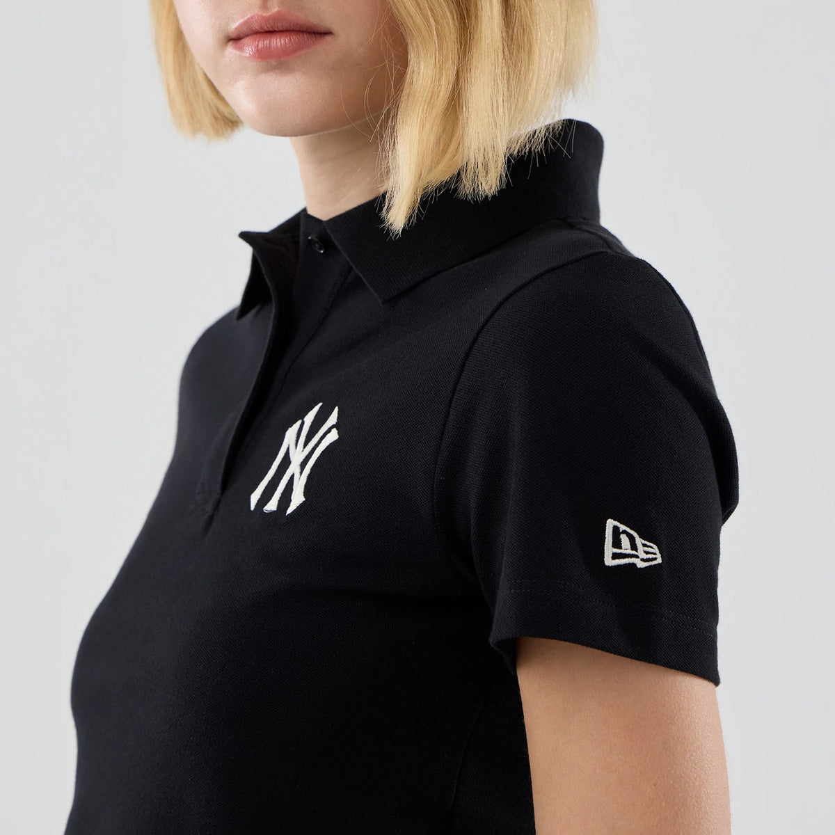 New Era New York Yankees Womens MLB Black Cropped Slim Polo T-shirt, front view showing the embroidered white NY logo on the chest and the embroidered New Era flag logo on the sleeve, styled simply on a model.