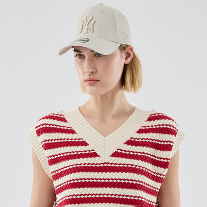 New Era New York Yankees Womens MLB Knit Stripe Dark Red Sleeveless V-neck Sweater, on-model front view showing a cream knitted v-neck design with red horizontal stripes, styled with a beige cap featuring an embroidered NY logo.