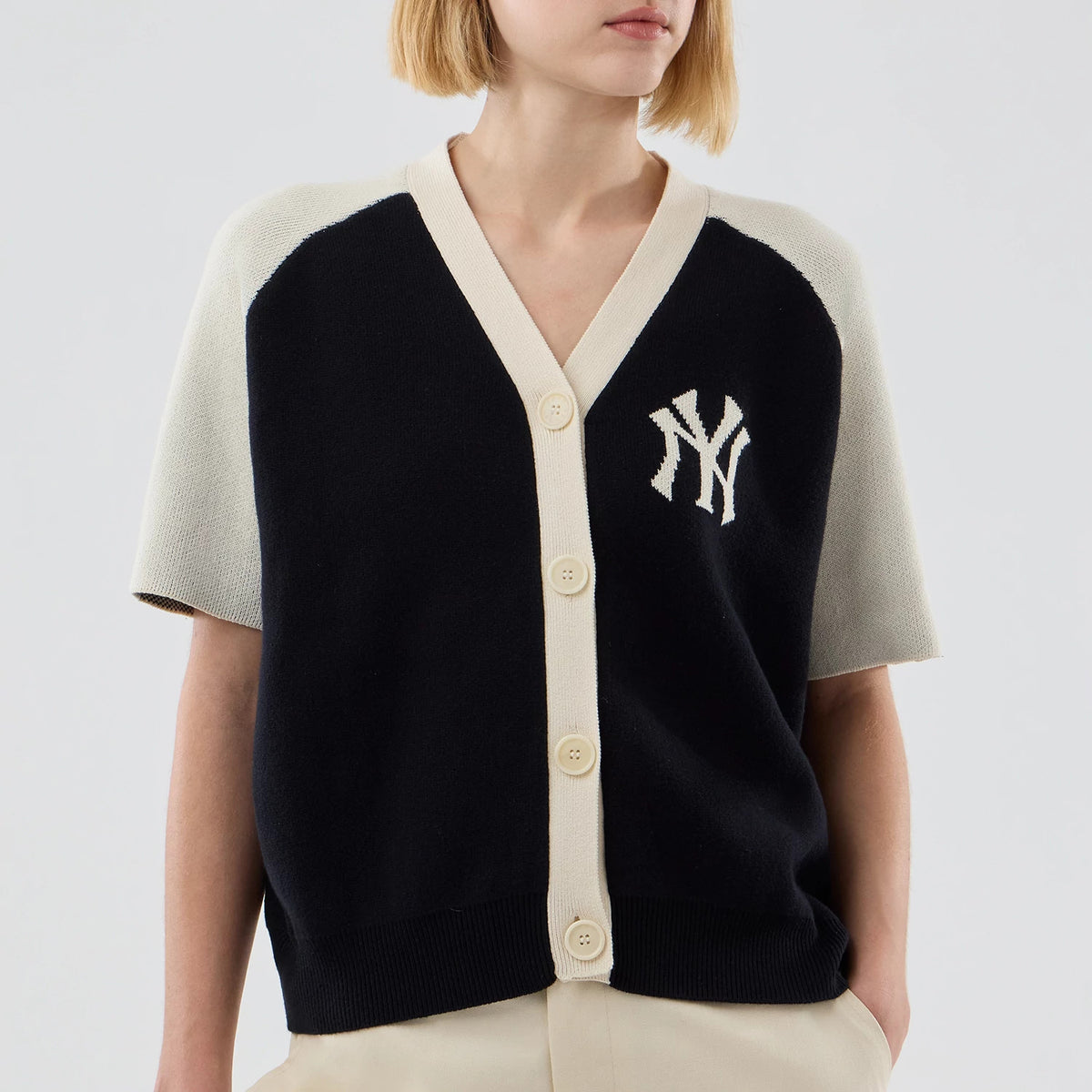 New Era New York Yankees Womens MLB Knit Stripe Black Short Sleeve Cardigan, front view on a model showing the white embroidered NY logo on the left chest, contrasting beige buttons along the front placket, and short sleeves with black.