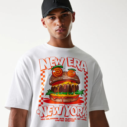 New Era Burger Food Graphic White Oversized T-Shirt, front view on-model showcasing a vivid burger graphic with red New Era and New York text across the chest, complemented by a black cap.