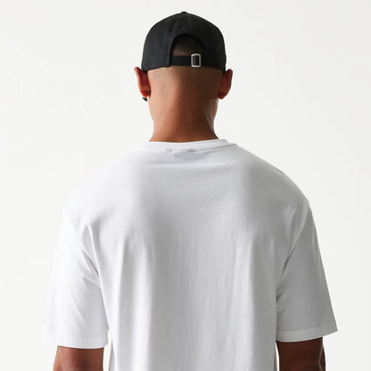 New Era Burger Food Graphic White Oversized T-Shirt, back view on a model wearing a black cap, displaying the plain white fabric and loose fit with a simple round neckline and short sleeves.