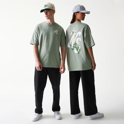 New Era Floral Graphic Pastel Green Oversized T-Shirt, front and back view on models showcasing a pastel green tee with an embroidered logo on the chest and a large floral graphic on the back, styled with black trousers and caps.
