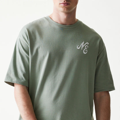 New Era Floral Graphic Pastel Green Oversized T-Shirt, front view on-model showing a pastel green body with a white embroidered New Era logo on the left chest, short sleeves and a relaxed fit.