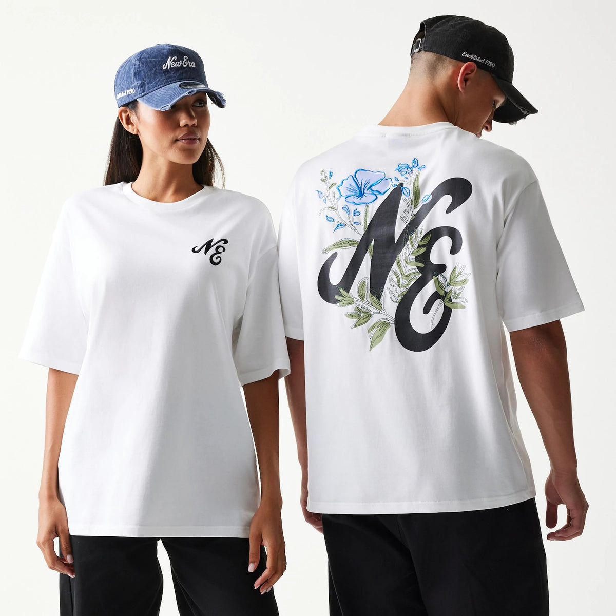 New Era Floral Graphic White Oversized T-Shirt, front and back view on models wearing caps, showing a black embroidered NE logo on the chest and a large NE design with floral graphics in blue and green on the upper back.