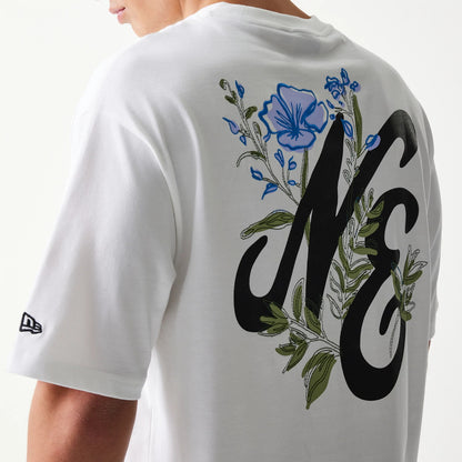 New Era Floral Graphic White Oversized T-Shirt, three-quarter view showing the large black NE lettering on the back surrounded by blue and green floral graphics, with a small embroidered New Era logo on the sleeve.