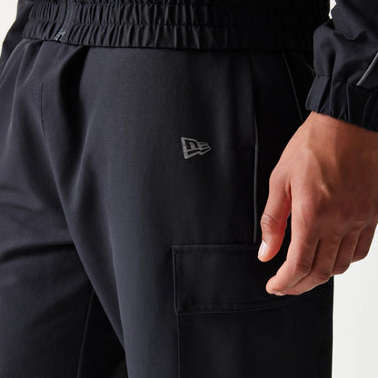 New Era New York Yankees MLB Utility Black Straight Leg Cargo Joggers, side view showing the grey New Era flag logo on the left thigh, large cargo pocket with a flap, and an elastic waistband with stitching details.
