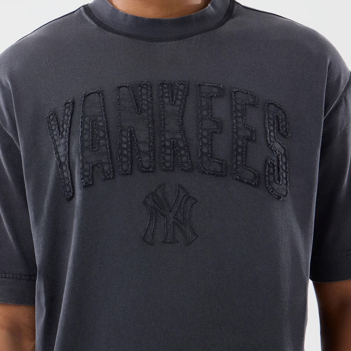 New Era New York Yankees MLB Washed Black T-Shirt, front view showing the textured embroidered Yankees lettering in large font across the chest, with a smaller raised New York Yankees logo beneath on a washed black fabric.