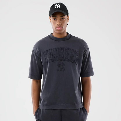 New Era New York Yankees MLB Washed Black T-Shirt, front view on-model featuring large embroidered Yankees lettering across the chest below a small Yankees logo, styled with a black cap with a raised white New Era logo.