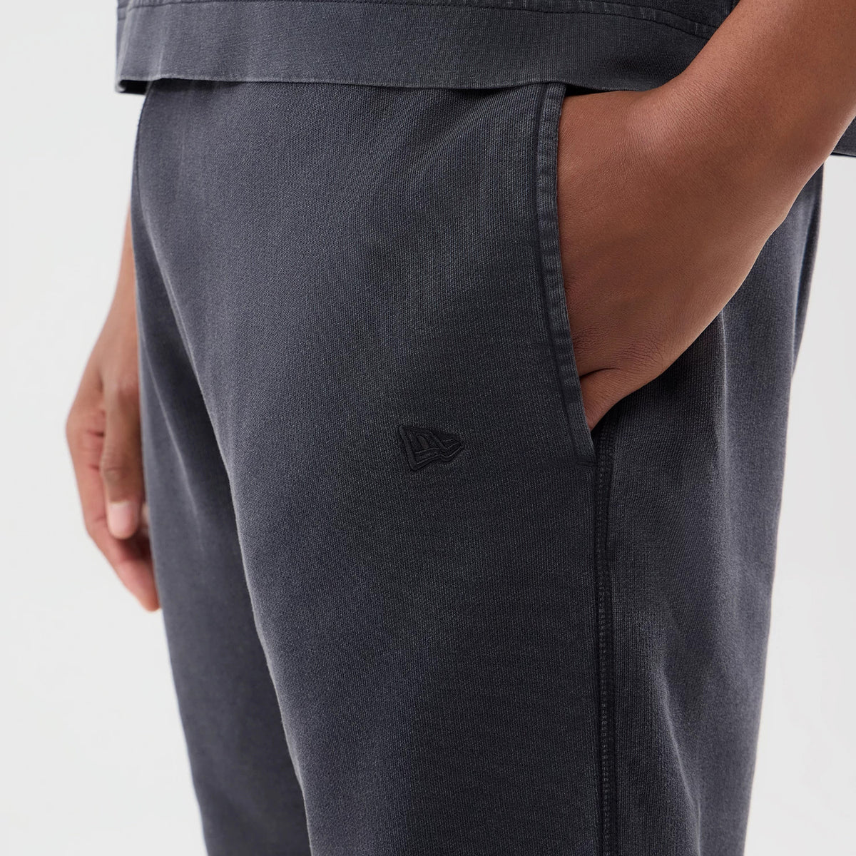 New Era New York Yankees MLB Washed Black Shorts, three-quarter view showing a hand in the side pocket, with a embroidered New Era logo on the thigh, illustrating a black design and casual fit.