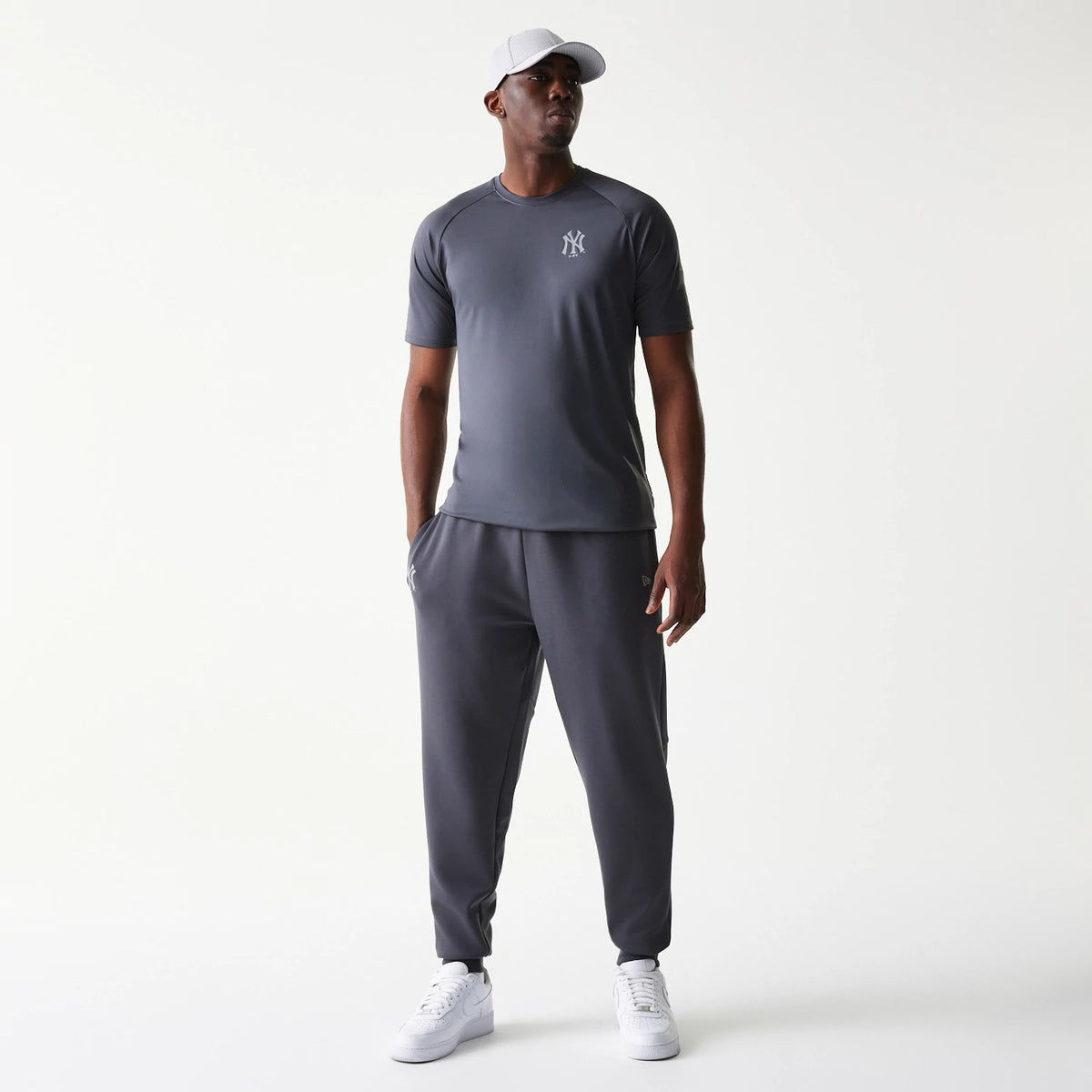 New Era New York Yankees MLB Dark Grey Joggers, on-model front view showing the joggers with an elastic waistband and cuffed ankles, featuring side pockets and a small Yankees logo on the upper left leg.