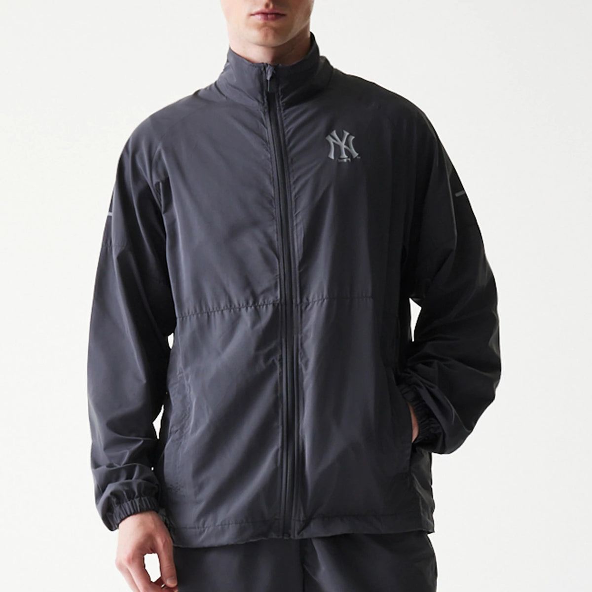New Era New York Yankees MLB Dark Grey Jacket, front view showing the full-length zip closure and elasticated cuffs, with the Yankees' logo embroidered on the left chest and a clean, finish across the dark grey fabric.